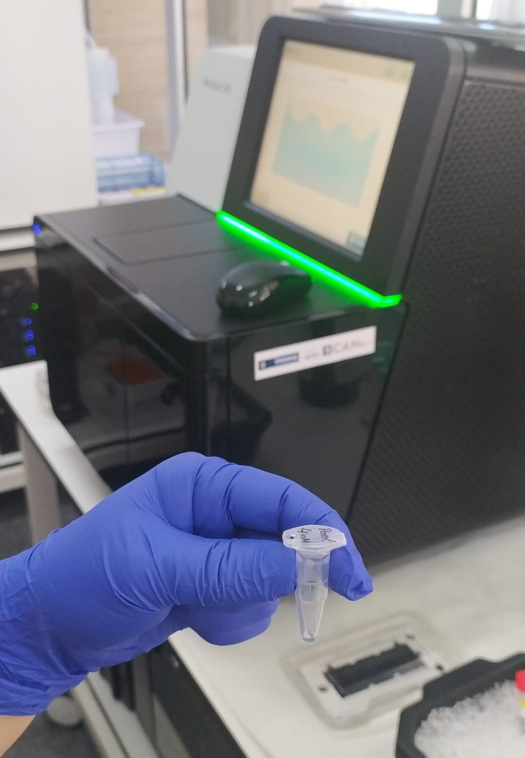 En primer plano, vial con 400 muestras positivas para SARS-CoV-2 de todo el archipiélago; en segundo plano, el secuenciador NextSeq550 que se utiliza para identificar las variantes circulantes de preocupación del coronavirus.